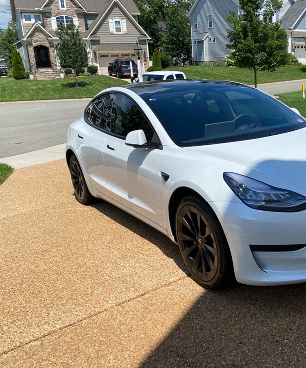 A White Telsa Model 3 in a driveway